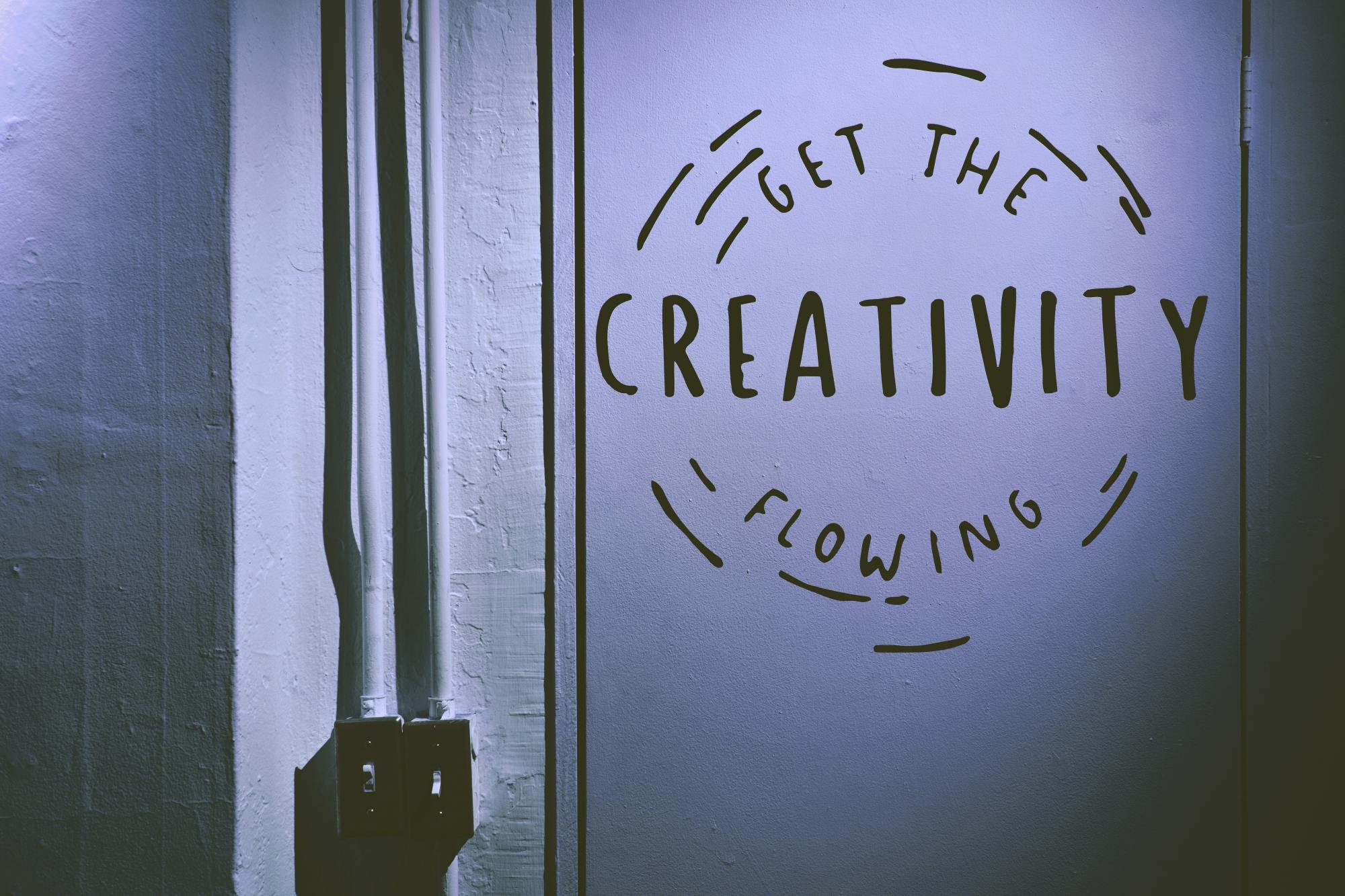 Artwork on a wall that says "Get the creativity flowing" to help avoid creative blocks at work